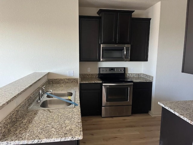 kitchen with sink, appliances with stainless steel finishes, and light hardwood / wood-style flooring
