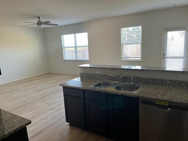 kitchen featuring ceiling fan, sink, stainless steel dishwasher, stone countertops, and light wood-type flooring