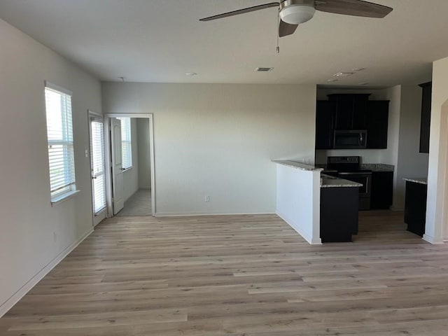 kitchen with light wood-type flooring, black range with electric stovetop, ceiling fan, and light stone counters