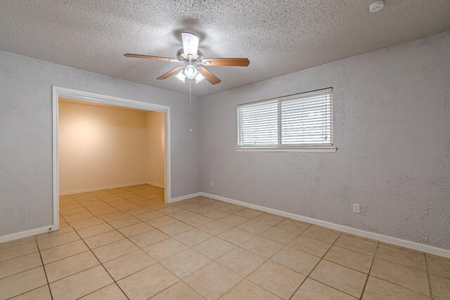 tiled empty room featuring ceiling fan and a textured ceiling