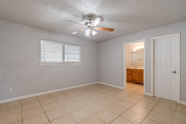 unfurnished bedroom with connected bathroom, ceiling fan, sink, a textured ceiling, and light tile patterned floors