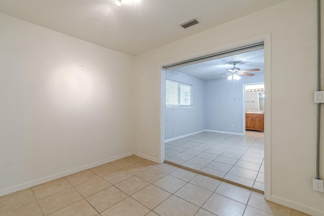 tiled spare room with ceiling fan