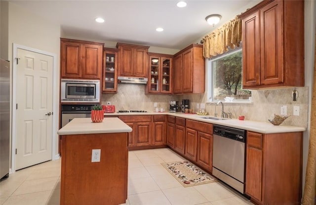 kitchen featuring a center island, sink, decorative backsplash, light tile patterned floors, and appliances with stainless steel finishes