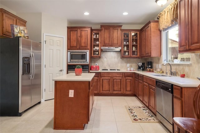 kitchen featuring sink, light tile patterned flooring, decorative backsplash, a kitchen island, and appliances with stainless steel finishes