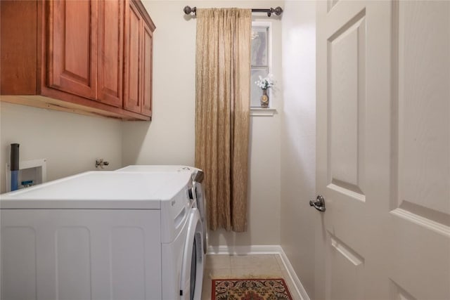 laundry room featuring washing machine and dryer, light tile patterned floors, and cabinets