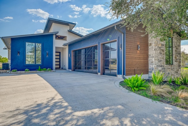 view of front of house with a garage and central air condition unit