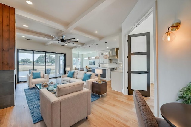 living room with beamed ceiling, ceiling fan, sink, and light hardwood / wood-style flooring