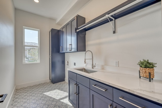 kitchen with light tile patterned flooring, light stone countertops, and sink