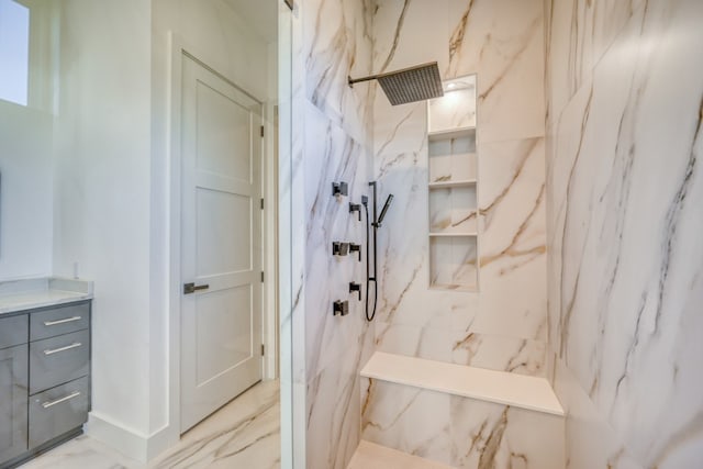 bathroom with a tile shower and vanity