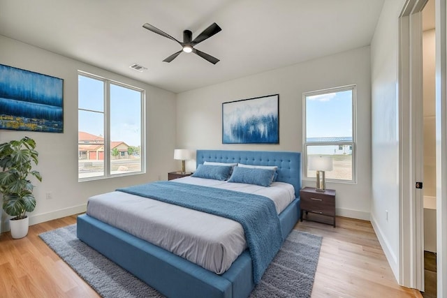 bedroom with ceiling fan, light hardwood / wood-style flooring, and multiple windows