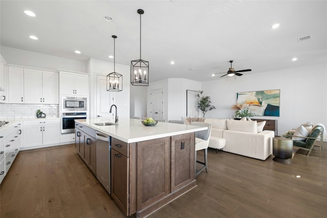 kitchen featuring sink, stainless steel appliances, an island with sink, white cabinets, and dark hardwood / wood-style flooring