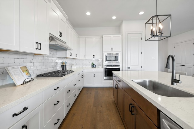 kitchen with white cabinetry, appliances with stainless steel finishes, decorative light fixtures, and sink