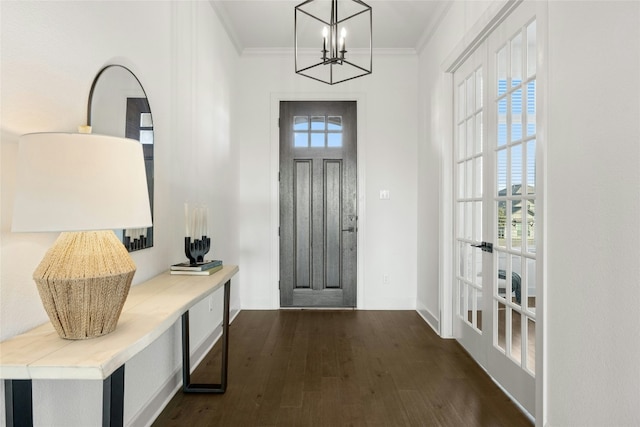 foyer entrance featuring french doors, dark hardwood / wood-style flooring, crown molding, and a notable chandelier