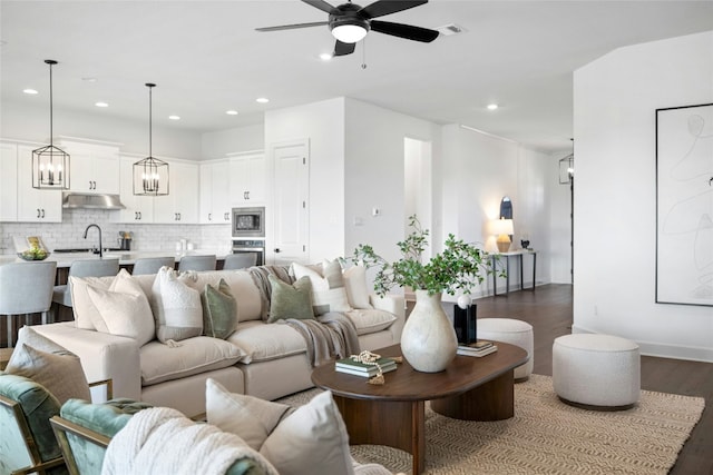 living room featuring dark wood-type flooring, sink, and ceiling fan