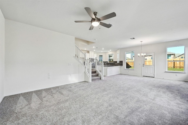 unfurnished living room featuring carpet flooring and ceiling fan with notable chandelier