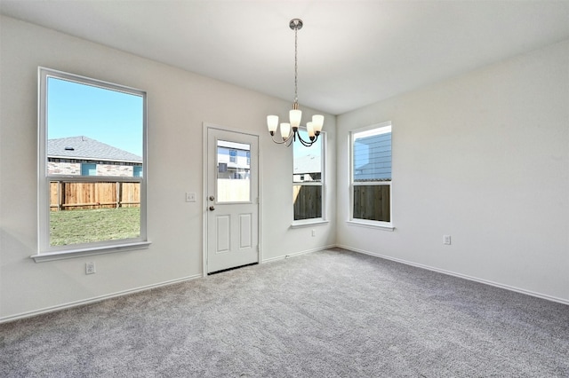 carpeted empty room featuring an inviting chandelier