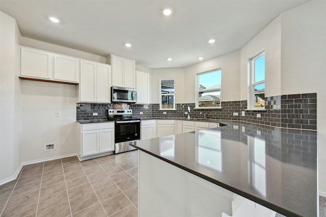 kitchen with white cabinets, light tile patterned floors, appliances with stainless steel finishes, tasteful backsplash, and kitchen peninsula