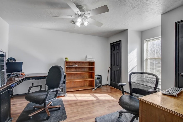 office area with a textured ceiling, light hardwood / wood-style floors, and ceiling fan