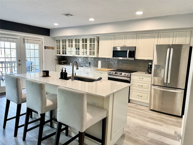 kitchen with french doors, stainless steel appliances, a breakfast bar area, and sink