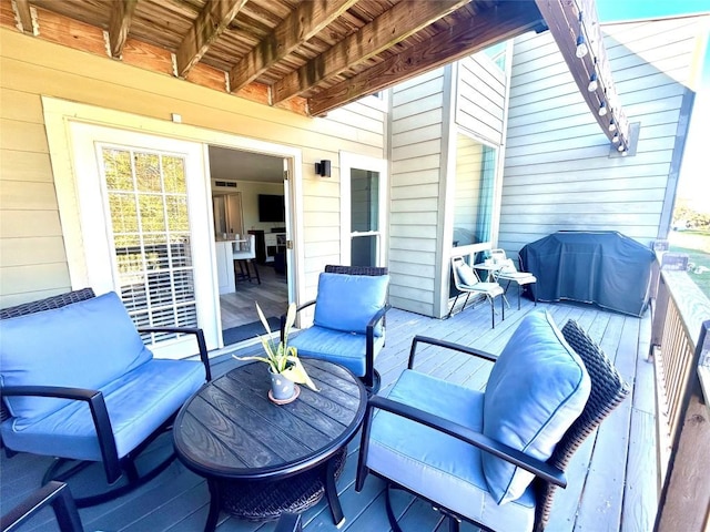 wooden terrace with an outdoor hangout area and grilling area