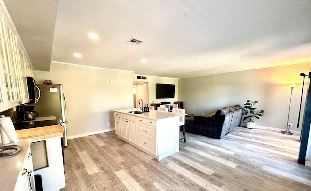 kitchen featuring a kitchen breakfast bar, light wood-type flooring, crown molding, sink, and a center island with sink