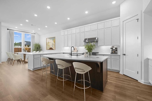 208 San Xavier St, Georgetown, TX 78633 - kitchen featuring a sink, under cabinet range hood, a center island with sink, a breakfast bar area, and recessed lighting
