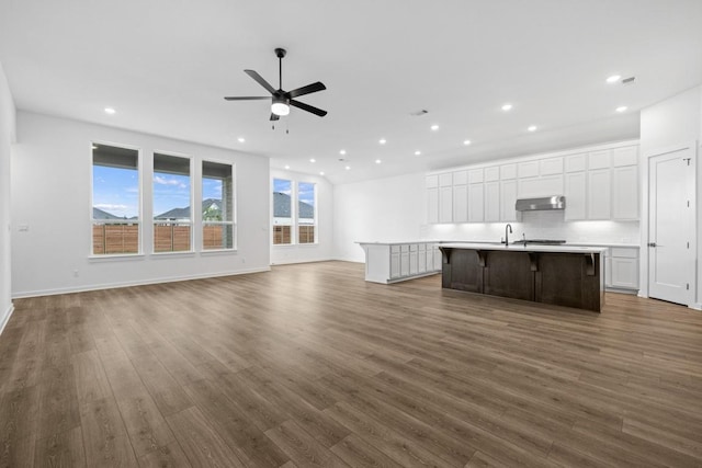 208 San Xavier St, Georgetown, TX 78633 - unfurnished living room with a ceiling fan, recessed lighting, dark wood-style flooring, baseboards, and a sink