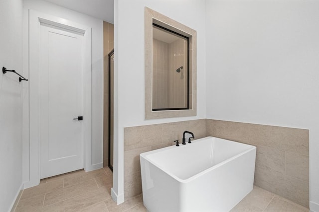 208 San Xavier St, Georgetown, TX 78633 - bathroom featuring a freestanding bath, a stall shower, tile patterned flooring, and tile walls