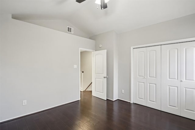 unfurnished bedroom with ceiling fan, a closet, dark wood-type flooring, and lofted ceiling