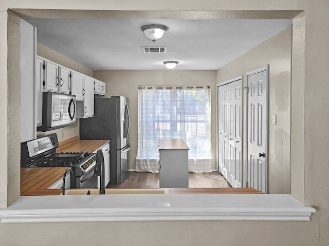 kitchen featuring white cabinets, stainless steel fridge, kitchen peninsula, and black range oven