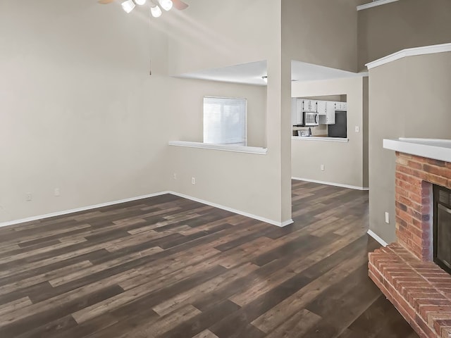 unfurnished living room with dark hardwood / wood-style flooring and a brick fireplace