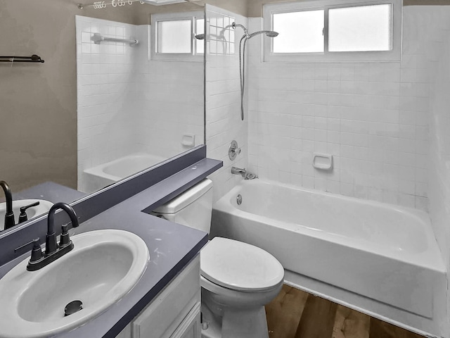 full bathroom featuring vanity, hardwood / wood-style flooring, toilet, and tiled shower / bath combo