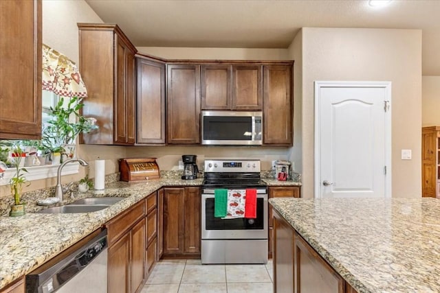 kitchen featuring light tile patterned flooring, appliances with stainless steel finishes, light stone counters, and sink