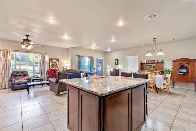 kitchen featuring dark brown cabinetry, ceiling fan, light tile patterned floors, a center island, and hanging light fixtures