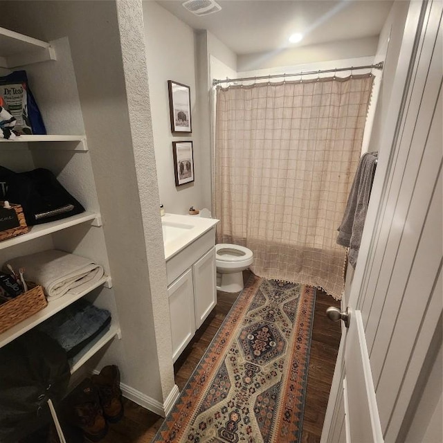 bathroom featuring walk in shower, vanity, wood-type flooring, and toilet