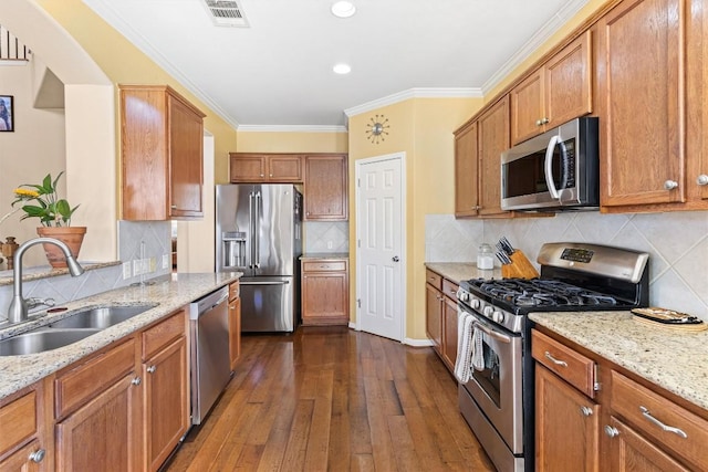 kitchen with light stone counters, sink, dark wood-type flooring, and appliances with stainless steel finishes