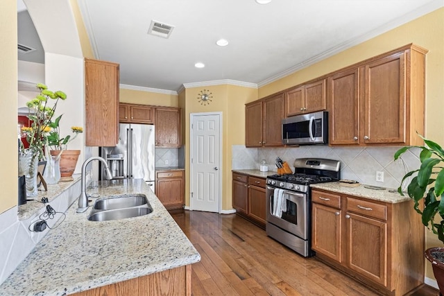 kitchen with light stone counters, sink, hardwood / wood-style floors, and appliances with stainless steel finishes