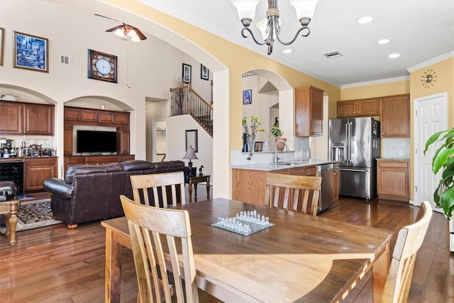 dining area with sink, a chandelier, dark hardwood / wood-style floors, and ornamental molding