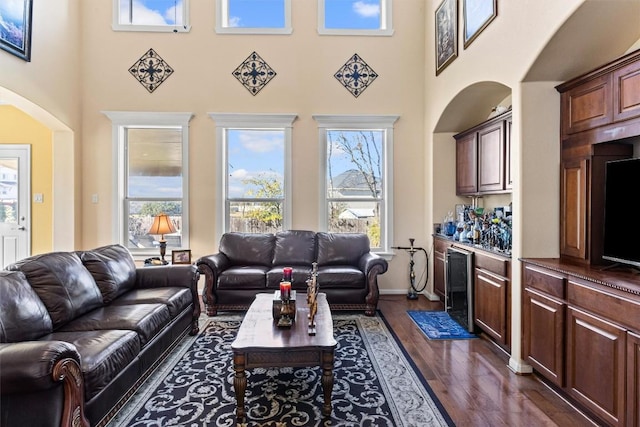 living room with dark hardwood / wood-style floors, beverage cooler, and a high ceiling