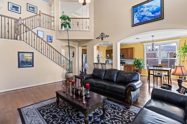 living room featuring a towering ceiling, hardwood / wood-style flooring, an inviting chandelier, and crown molding