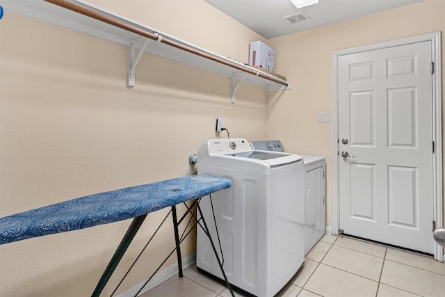 laundry area with separate washer and dryer and light tile patterned floors