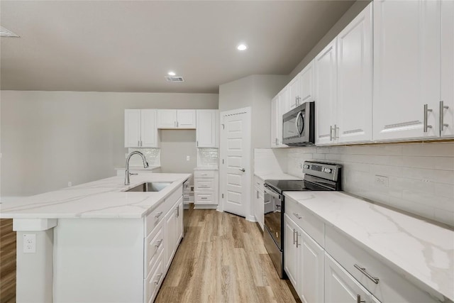 kitchen with white cabinets, sink, a center island with sink, and electric stove