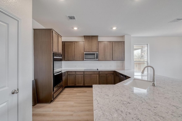 kitchen with stainless steel appliances, light wood-style flooring, a sink, and visible vents