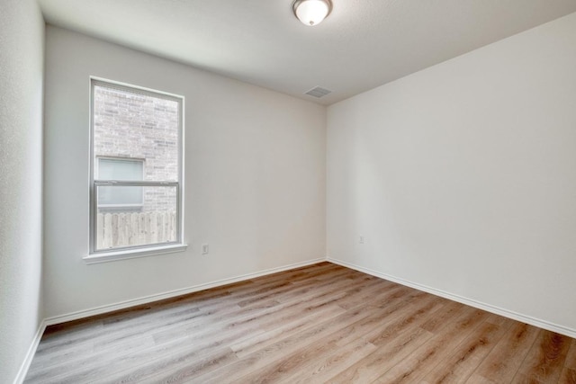 empty room featuring visible vents, baseboards, and wood finished floors