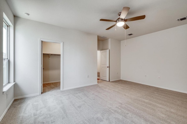 unfurnished bedroom with baseboards, visible vents, a spacious closet, and carpet flooring
