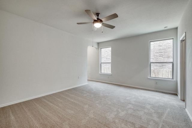 carpeted spare room with ceiling fan and baseboards