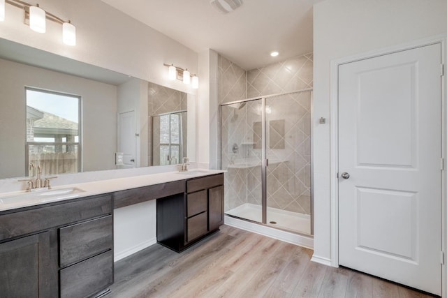bathroom with wood finished floors, a stall shower, and a sink