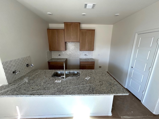 kitchen with light stone countertops, backsplash, and sink