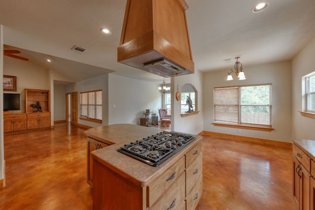 kitchen featuring a center island, premium range hood, hanging light fixtures, gas stovetop, and a textured ceiling