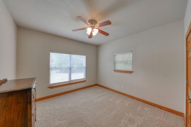 unfurnished room with light colored carpet and ceiling fan